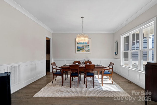 dining room featuring dark hardwood / wood-style flooring, crown molding, and a chandelier