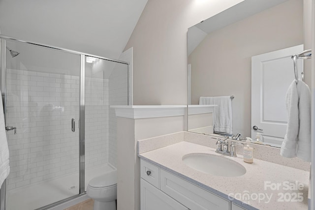 bathroom featuring vanity, vaulted ceiling, a shower with shower door, and toilet