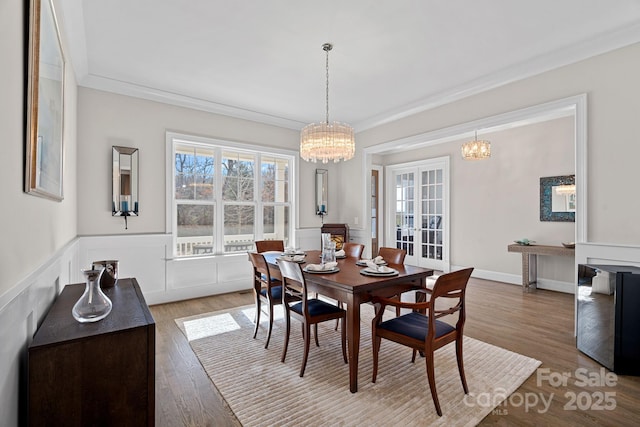 dining space featuring ornamental molding, wood-type flooring, and a chandelier