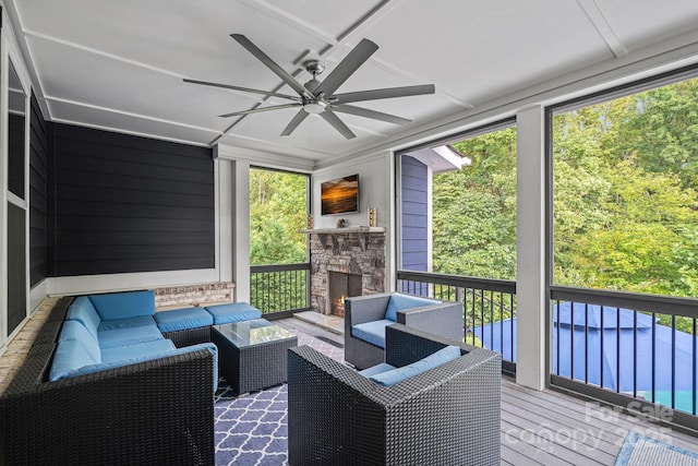 sunroom with a fireplace, ceiling fan, and plenty of natural light