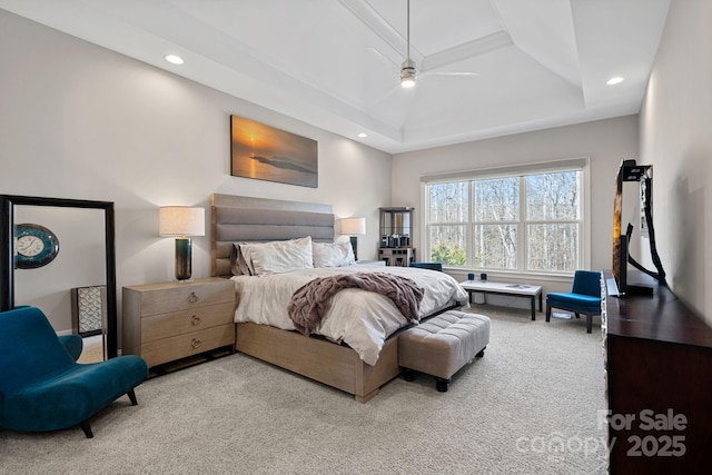 bedroom with ceiling fan, light colored carpet, and a raised ceiling