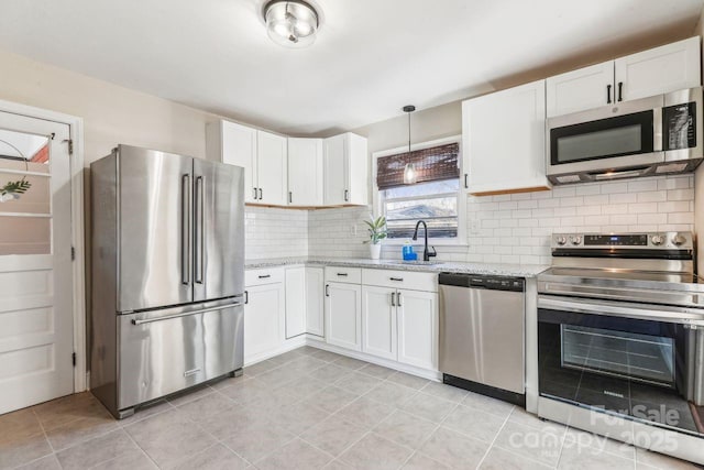 kitchen featuring light stone countertops, white cabinetry, appliances with stainless steel finishes, and sink