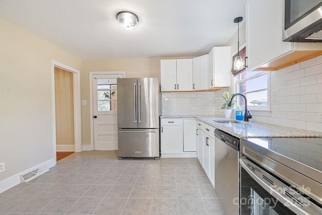 kitchen with white cabinetry, stainless steel appliances, sink, and light stone counters