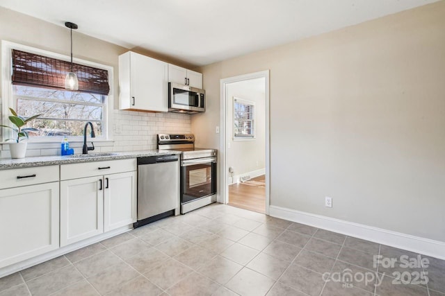 kitchen featuring light stone counters, decorative light fixtures, appliances with stainless steel finishes, white cabinets, and backsplash