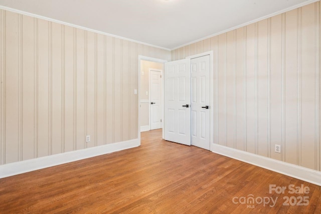 unfurnished bedroom featuring hardwood / wood-style floors, crown molding, and a closet