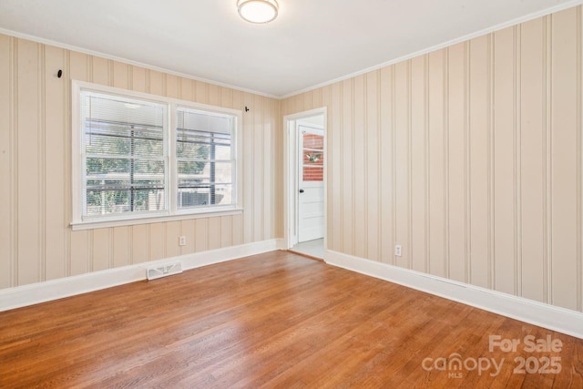 empty room with crown molding and hardwood / wood-style floors