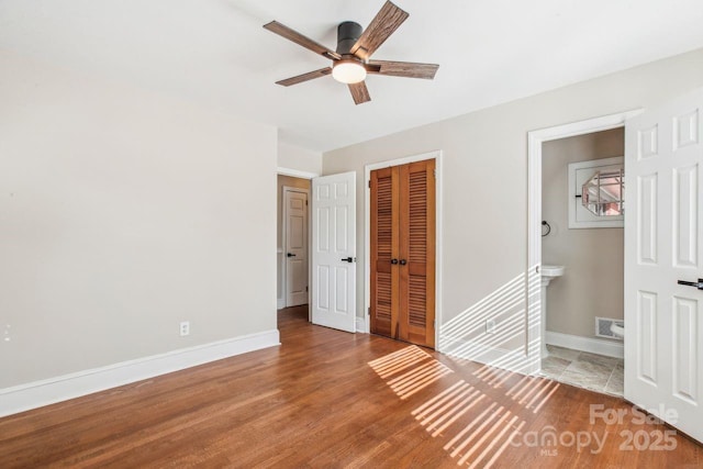 unfurnished bedroom featuring ensuite bathroom, a closet, ceiling fan, and light wood-type flooring