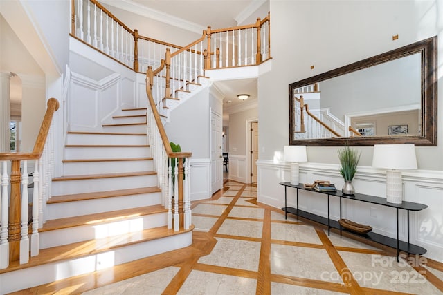 staircase featuring ornamental molding and a towering ceiling