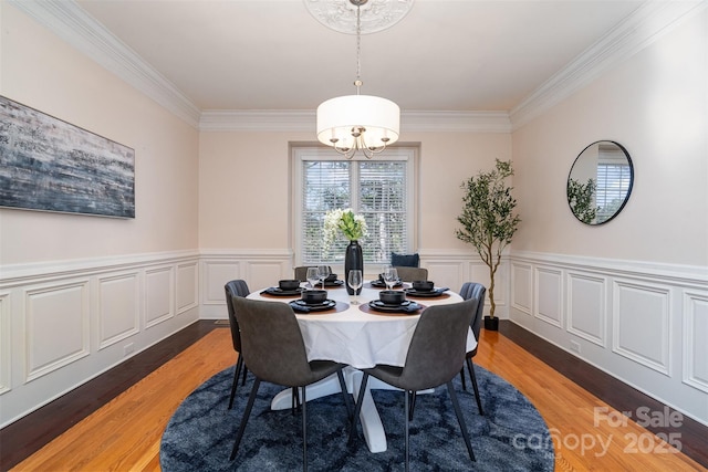 dining space featuring wood-type flooring, a notable chandelier, and crown molding