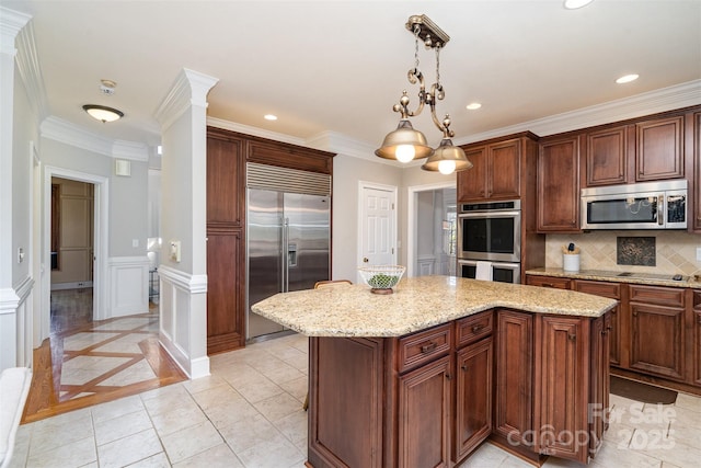 kitchen with tasteful backsplash, light stone counters, decorative light fixtures, appliances with stainless steel finishes, and a kitchen island