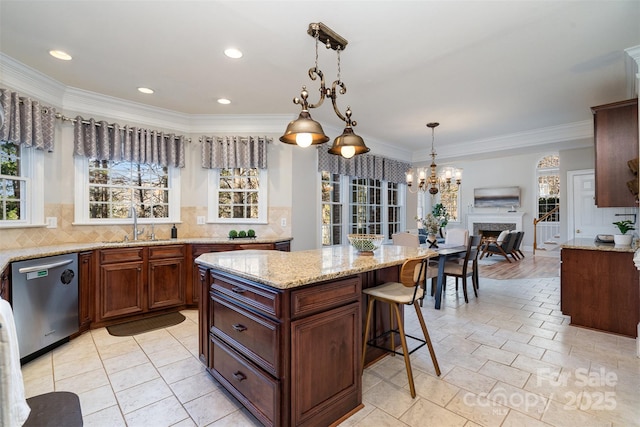 kitchen with pendant lighting, stainless steel dishwasher, light stone counters, and a kitchen island