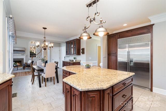 kitchen featuring ornamental molding, a kitchen island, stainless steel built in fridge, and hanging light fixtures