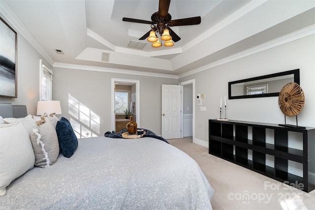 carpeted bedroom with crown molding, a raised ceiling, and multiple windows