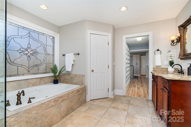 bathroom with tile patterned floors, vanity, and tiled tub