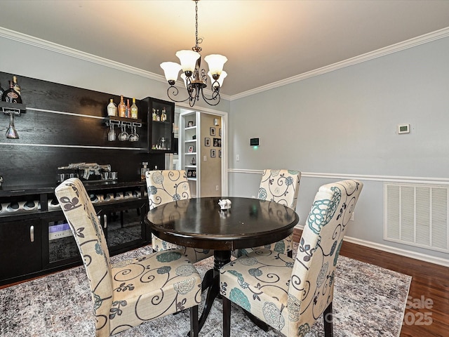 dining room featuring ornamental molding, a chandelier, and wood-type flooring