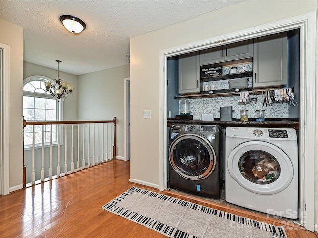 washroom with an inviting chandelier, separate washer and dryer, cabinets, hardwood / wood-style flooring, and a textured ceiling