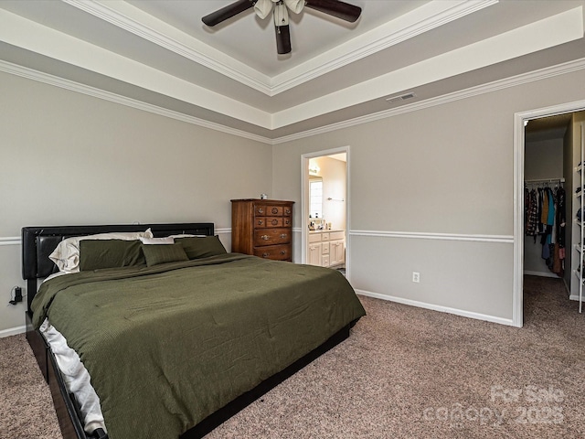 bedroom with a walk in closet, carpet flooring, and a tray ceiling