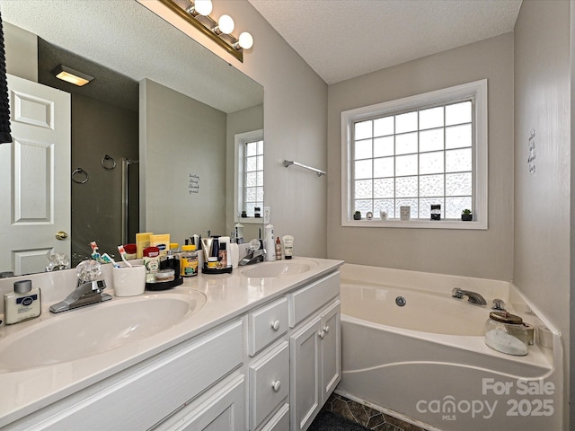 bathroom with a tub to relax in, a textured ceiling, and vanity