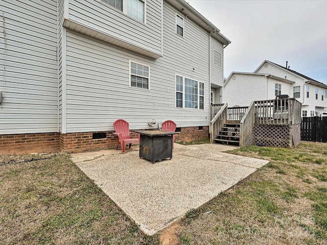 rear view of house featuring an outdoor fire pit, a deck, a patio, and a lawn