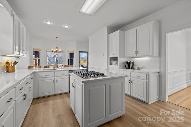 kitchen featuring sink, white cabinets, a kitchen island, decorative light fixtures, and kitchen peninsula