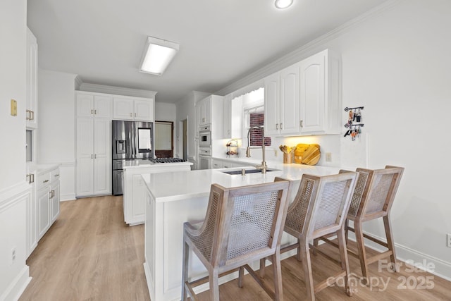 kitchen featuring kitchen peninsula, white cabinetry, sink, a kitchen bar, and stainless steel fridge with ice dispenser