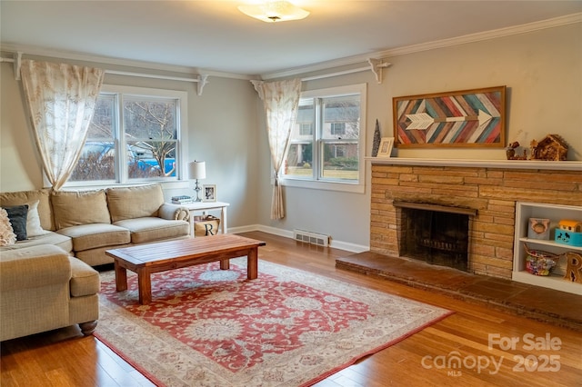 living room featuring hardwood / wood-style floors, crown molding, and a stone fireplace