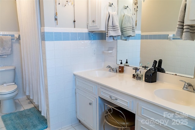 bathroom with vanity, toilet, tile patterned flooring, and tile walls