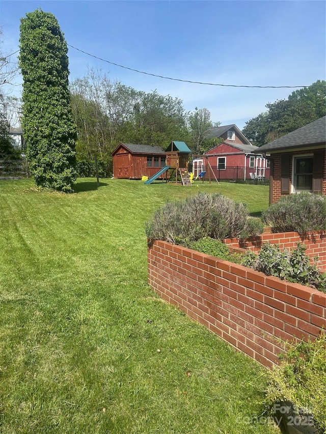 view of yard featuring an outdoor structure, a playground, and a storage unit