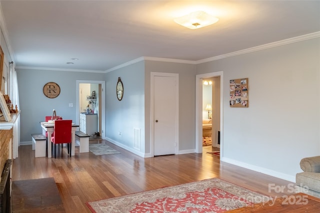 living area with baseboards, ornamental molding, wood finished floors, and visible vents