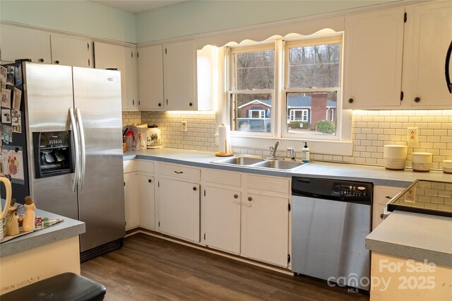 kitchen featuring a sink, appliances with stainless steel finishes, tasteful backsplash, and dark wood-style floors