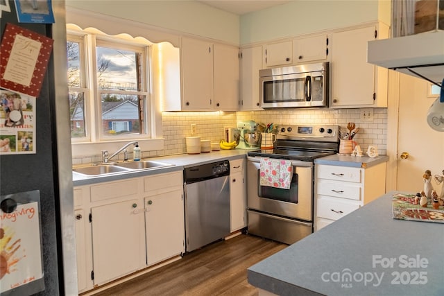 kitchen featuring a sink, light countertops, dark wood finished floors, stainless steel appliances, and tasteful backsplash