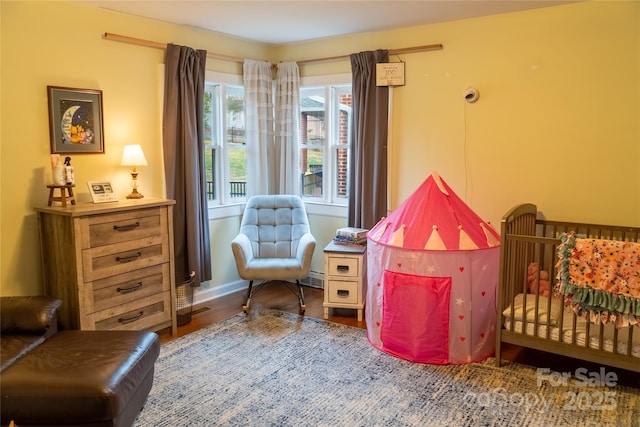 bedroom with baseboards, a baseboard radiator, and wood finished floors