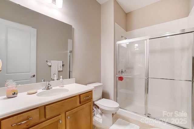 bathroom featuring toilet, vanity, and a shower with shower door