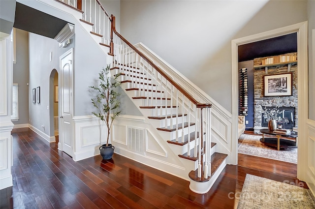 staircase featuring hardwood / wood-style flooring, a fireplace, and a high ceiling