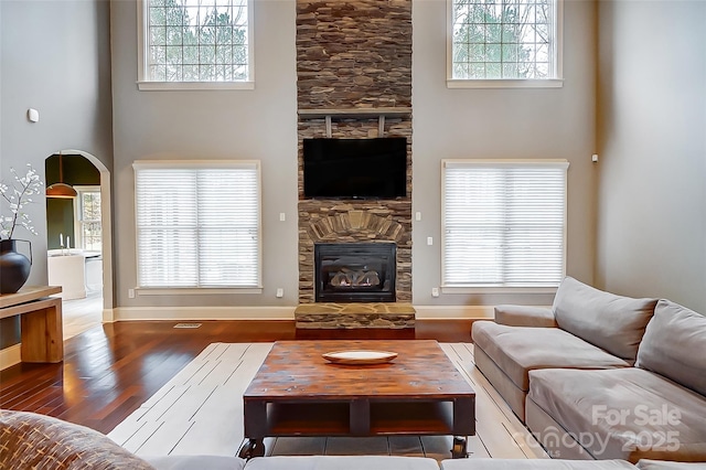 living room with plenty of natural light, dark hardwood / wood-style floors, a fireplace, and a towering ceiling