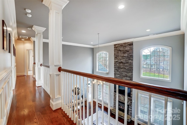 hallway with crown molding, hardwood / wood-style flooring, and decorative columns