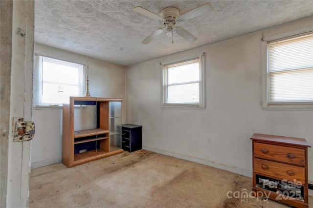 spare room featuring light carpet, ceiling fan, and a textured ceiling