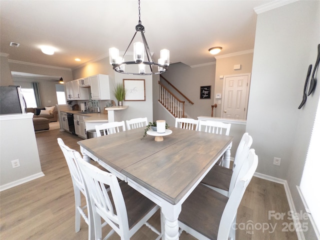 dining space with an inviting chandelier, sink, crown molding, and light hardwood / wood-style flooring