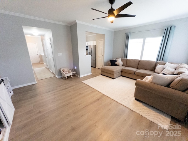 living room with ceiling fan, ornamental molding, and light wood-type flooring