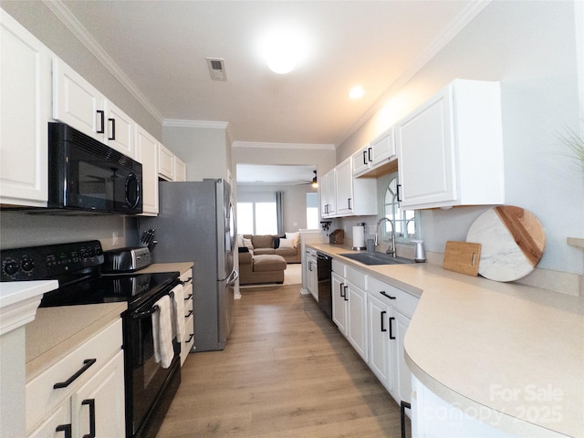 kitchen featuring sink, white cabinets, ornamental molding, light hardwood / wood-style floors, and black appliances