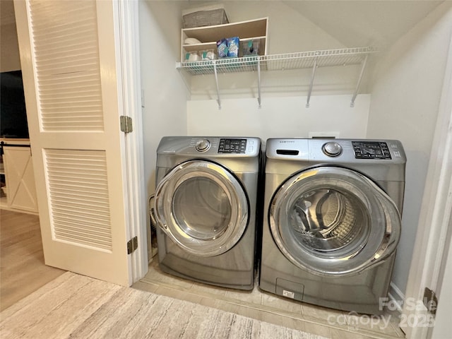 clothes washing area with washing machine and clothes dryer and light hardwood / wood-style flooring