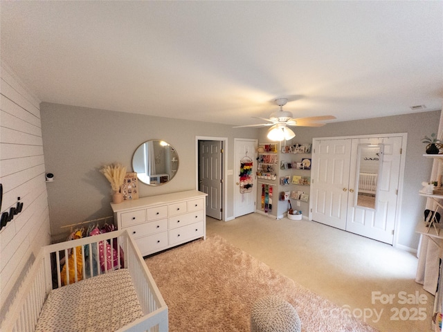 unfurnished bedroom featuring ceiling fan, light colored carpet, and wooden walls