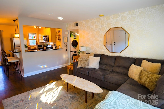 living room with stacked washer and dryer and dark wood-type flooring