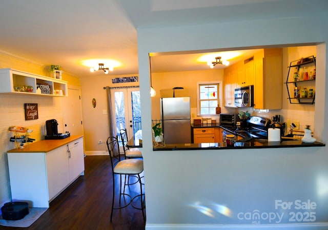 kitchen with french doors, kitchen peninsula, white cabinets, stainless steel appliances, and backsplash