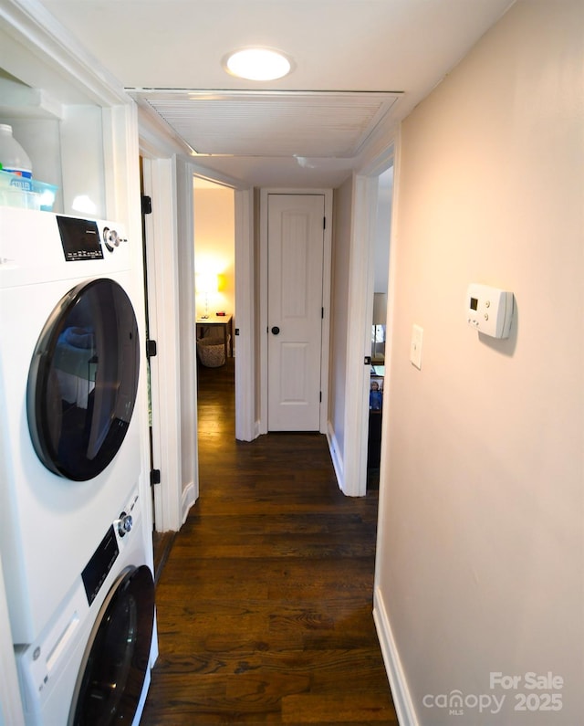 laundry area featuring stacked washer / drying machine and dark hardwood / wood-style flooring