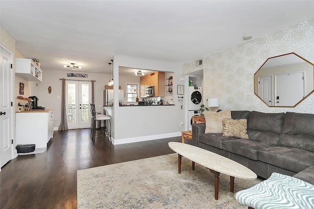 living room featuring dark wood-type flooring, french doors, and stacked washing maching and dryer