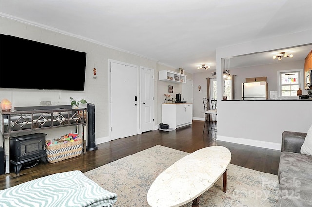 living room with dark wood-type flooring, ornamental molding, and a wood stove