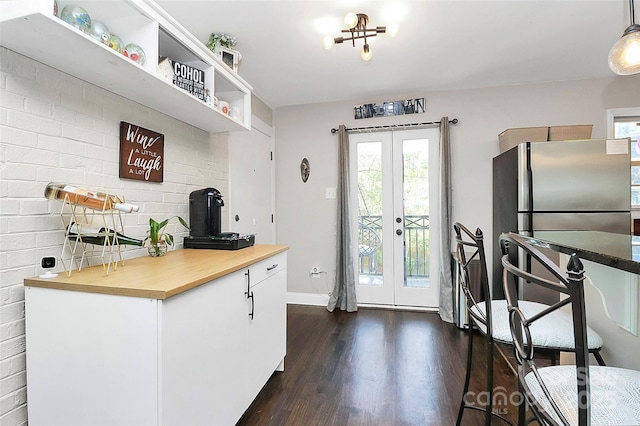 kitchen featuring dark hardwood / wood-style floors, pendant lighting, wood counters, white cabinetry, and french doors