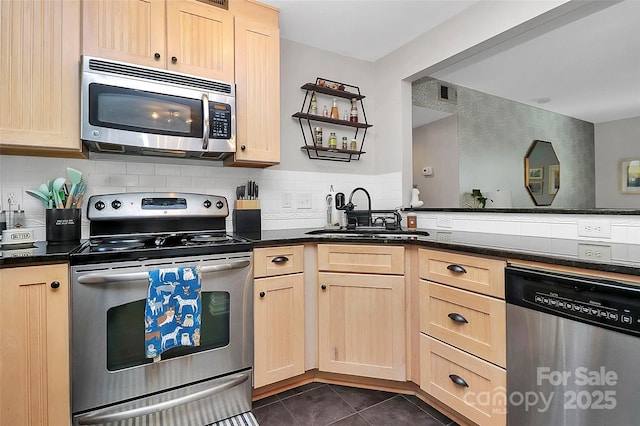 kitchen featuring light brown cabinetry, sink, dark tile patterned floors, and appliances with stainless steel finishes