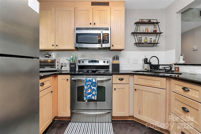 kitchen with appliances with stainless steel finishes, sink, light brown cabinetry, and decorative backsplash